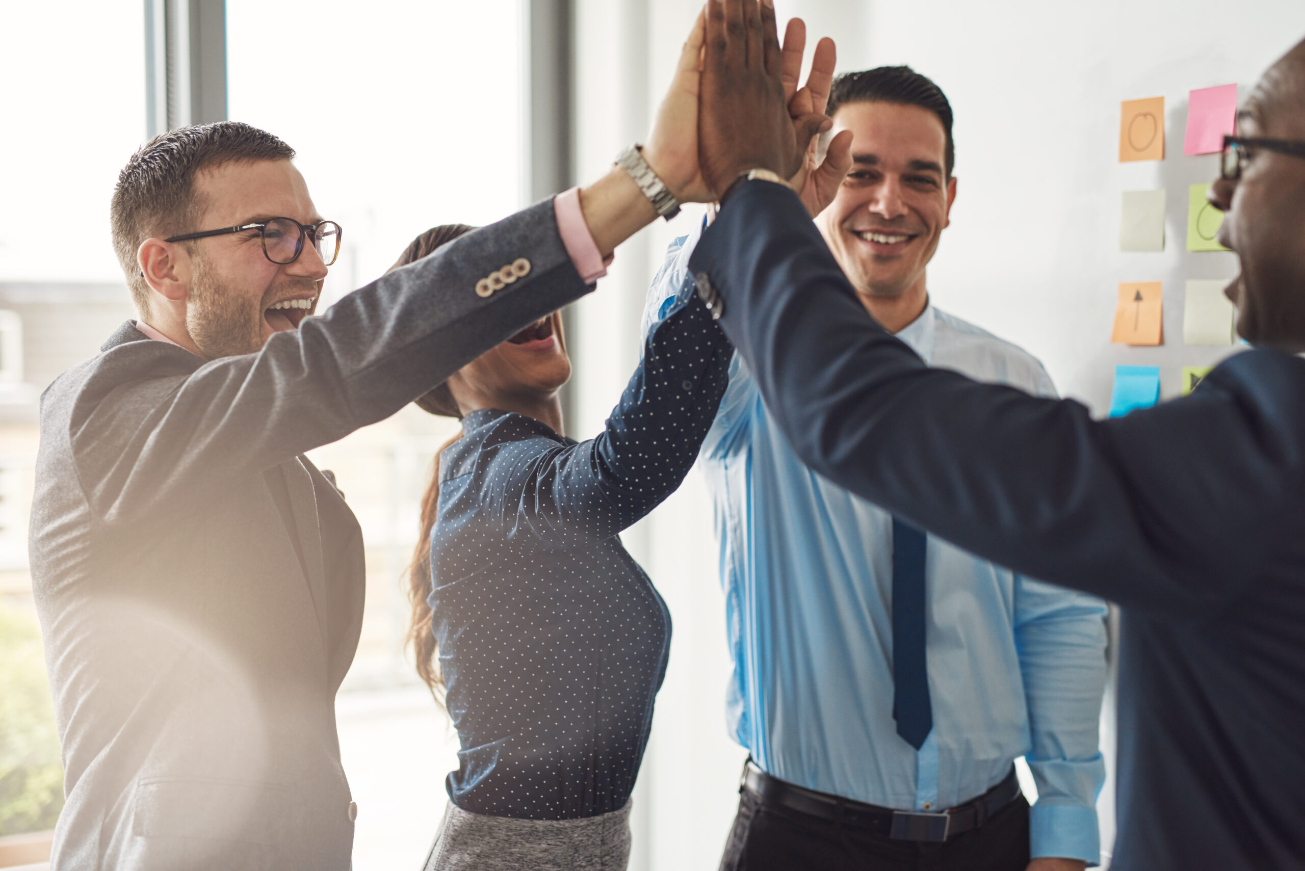 Happy successful multiracial business team giving a high fives gesture as they laugh and cheer their success